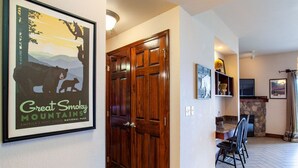 Een hal met een houten deur, een lijst met een poster van de Great Smoky Mountains, en een eethoek met stoelen en een tafel.