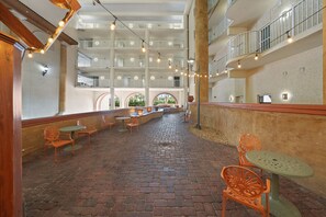 Guests can enjoy the tranquil atmosphere of our interior courtyard, featuring comfortable seating areas and a central staircase leading to upper-level balconies.