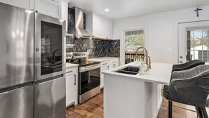 Una cocina moderna con electrodomésticos de acero inoxidable, salpicadero con motivo de espiga y una zona de bar con taburetes.