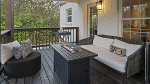 Un espacio de estar al aire libre con techo, que incluye una chimenea integrada, un banco acolchado y una mesa.