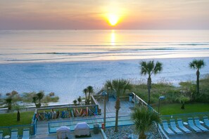 Enjoy a serene beachfront setting with a pool, lounge chairs, and umbrellas, perfect for relaxation.
