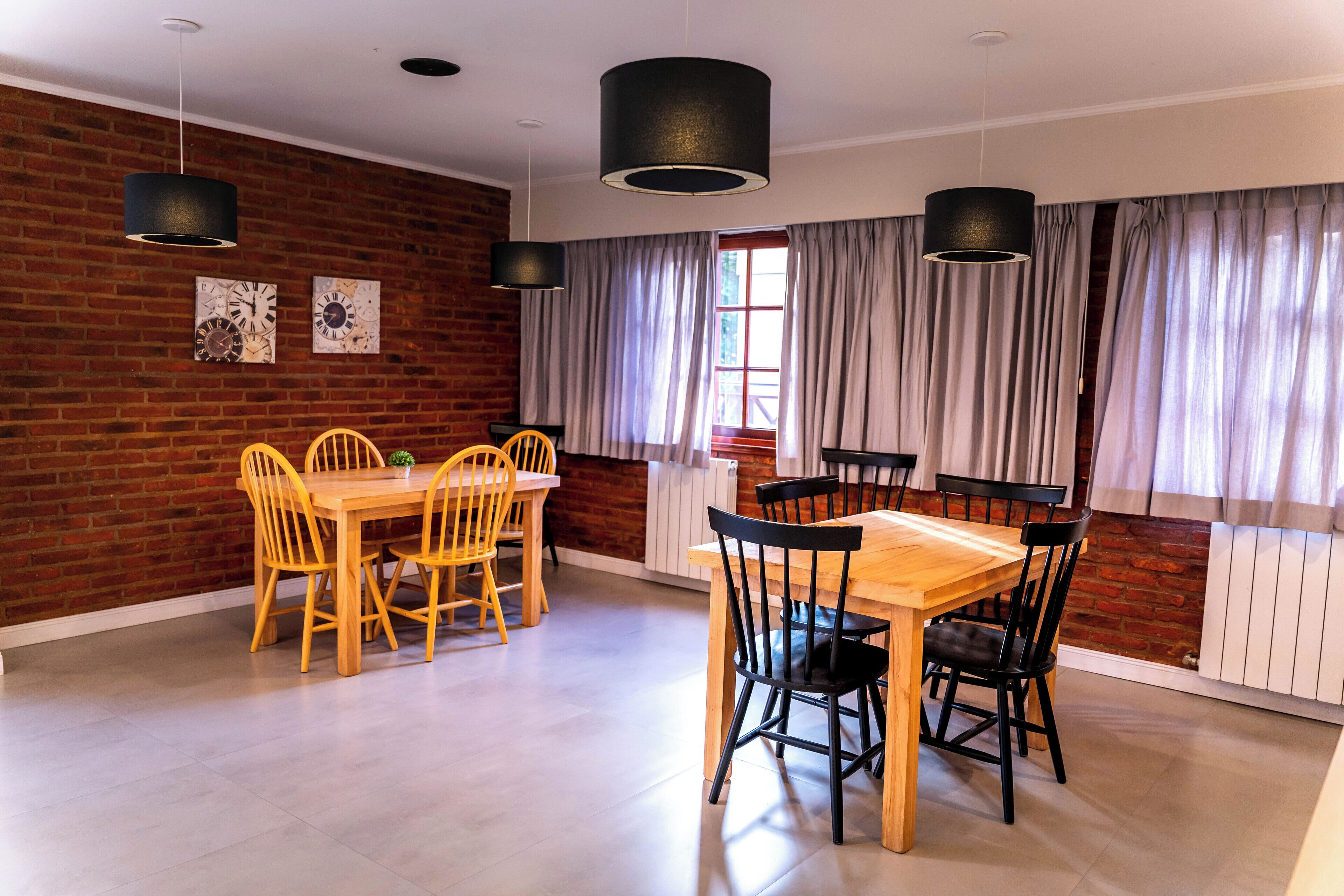 Un comedor con pared de ladrillo, mesa y sillas de madera.