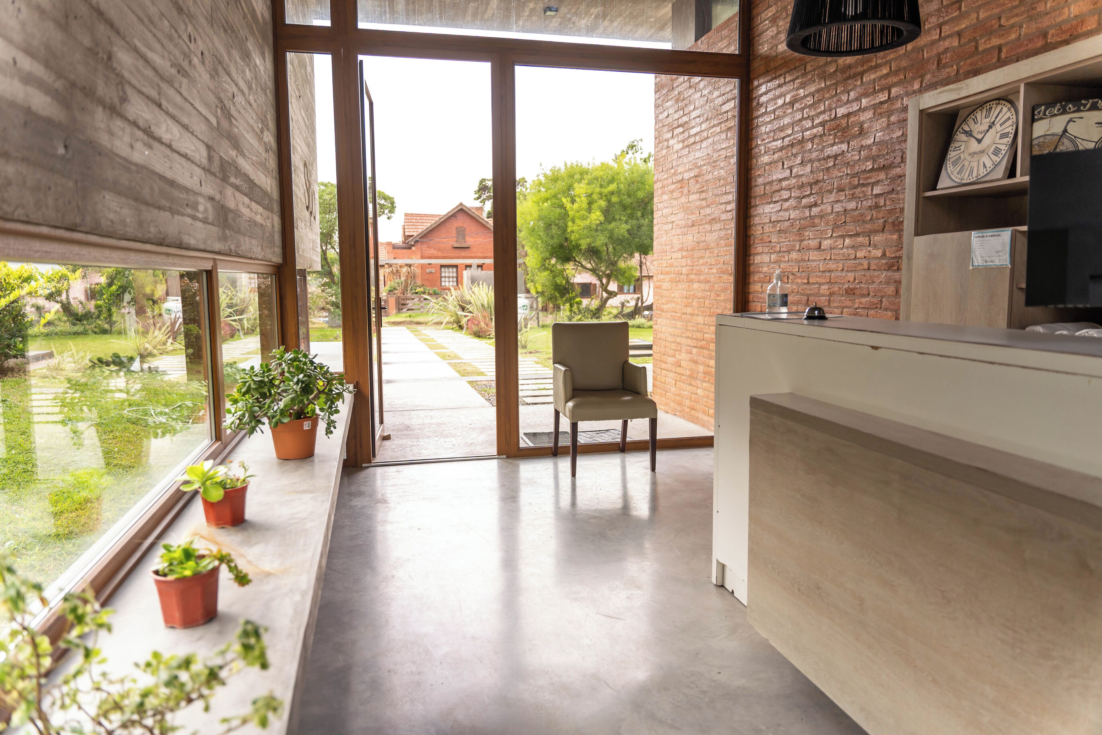 A modern kitchen with a large window, a chair, and potted plants.