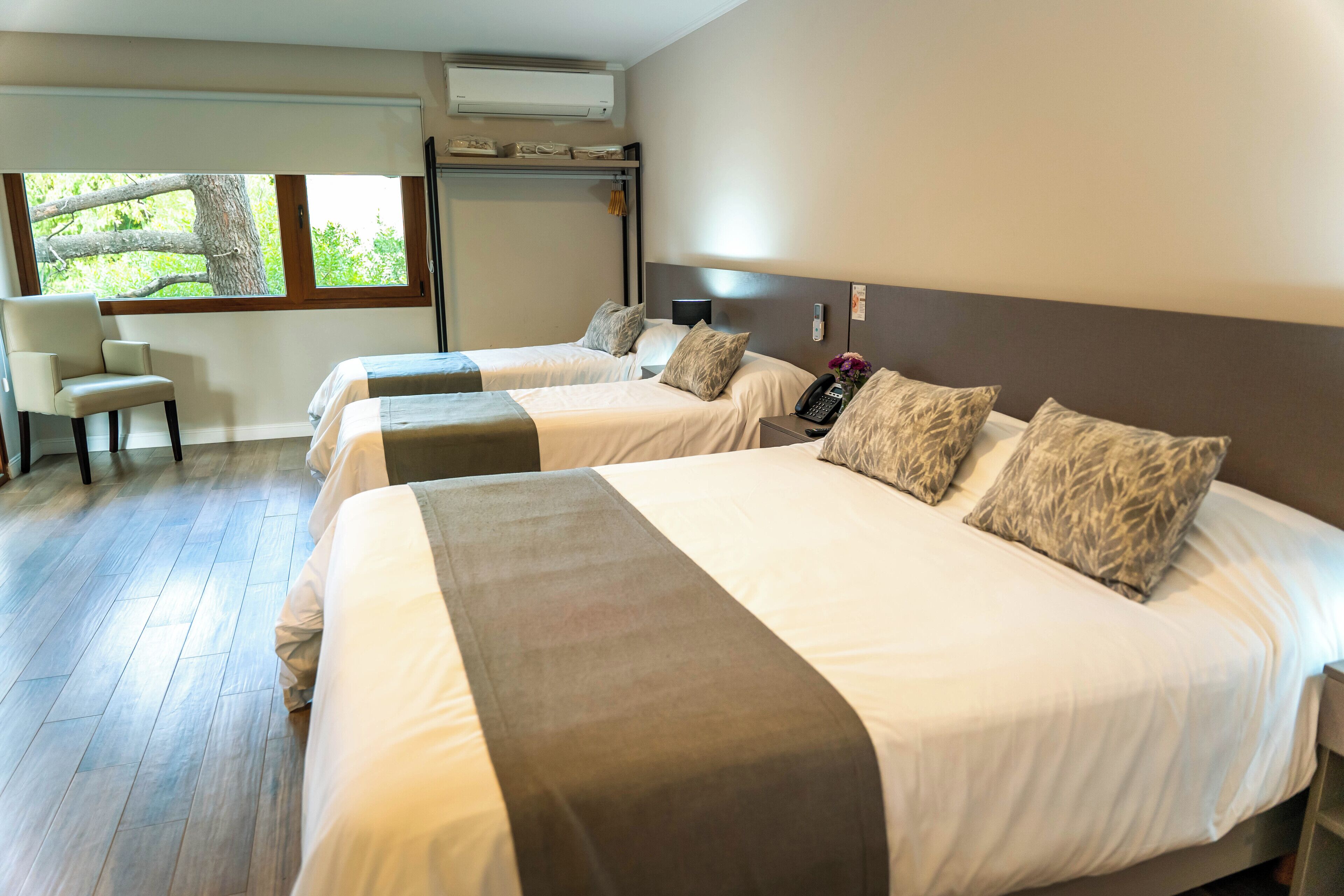 A hotel room with two beds, a desk, and a chair.