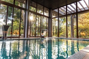 An indoor swimming pool with clear glass walls, a water fountain, and a view of trees outside. - O2 Hotel Valeria del Mar (Valeria del Mar)