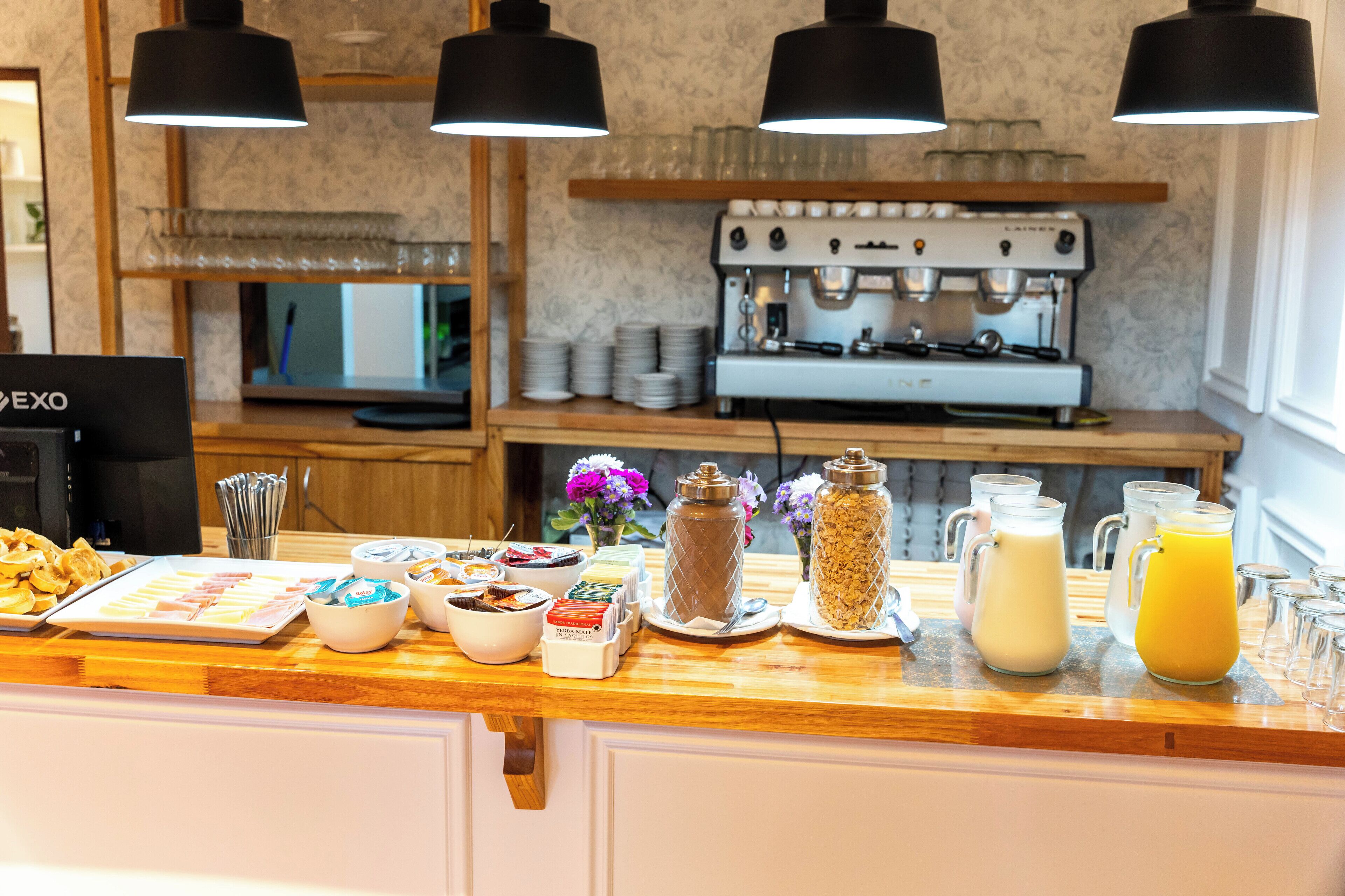 Una barra de desayuno con diferentes alimentos, una máquina de café y una caja registradora.