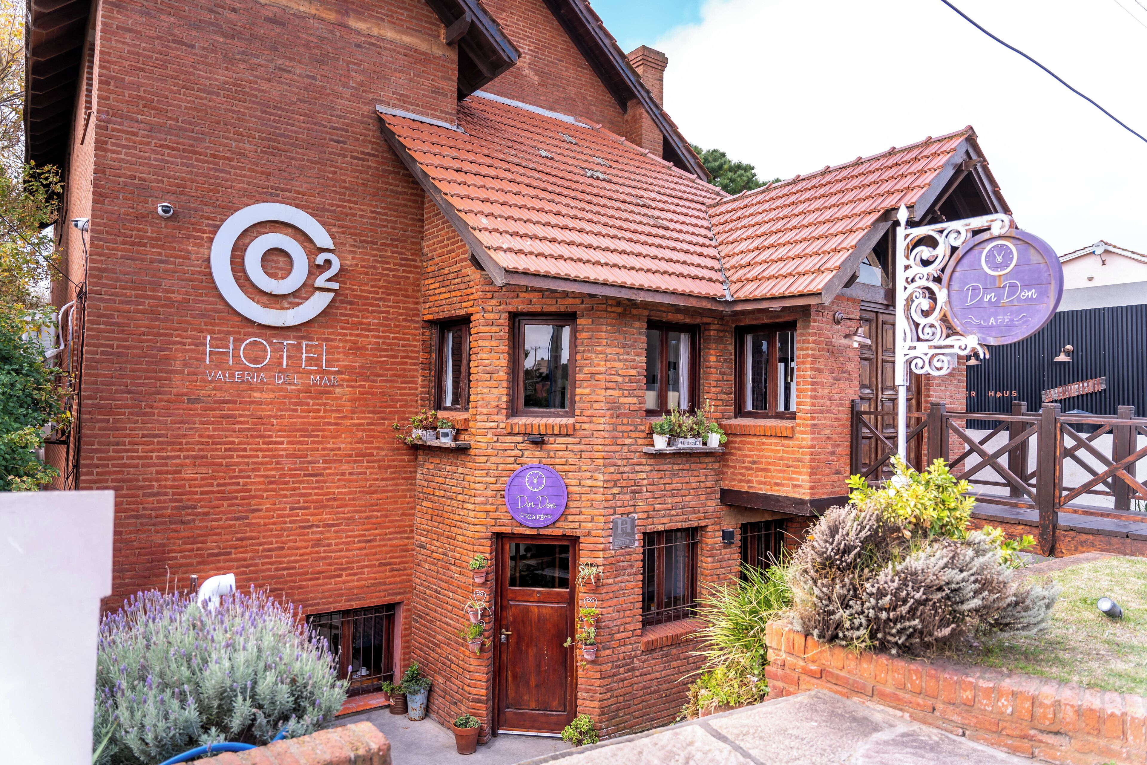 Un hotel con fachada de ladrillo, un cartel que indica Hotel O2 y un letrero de café.