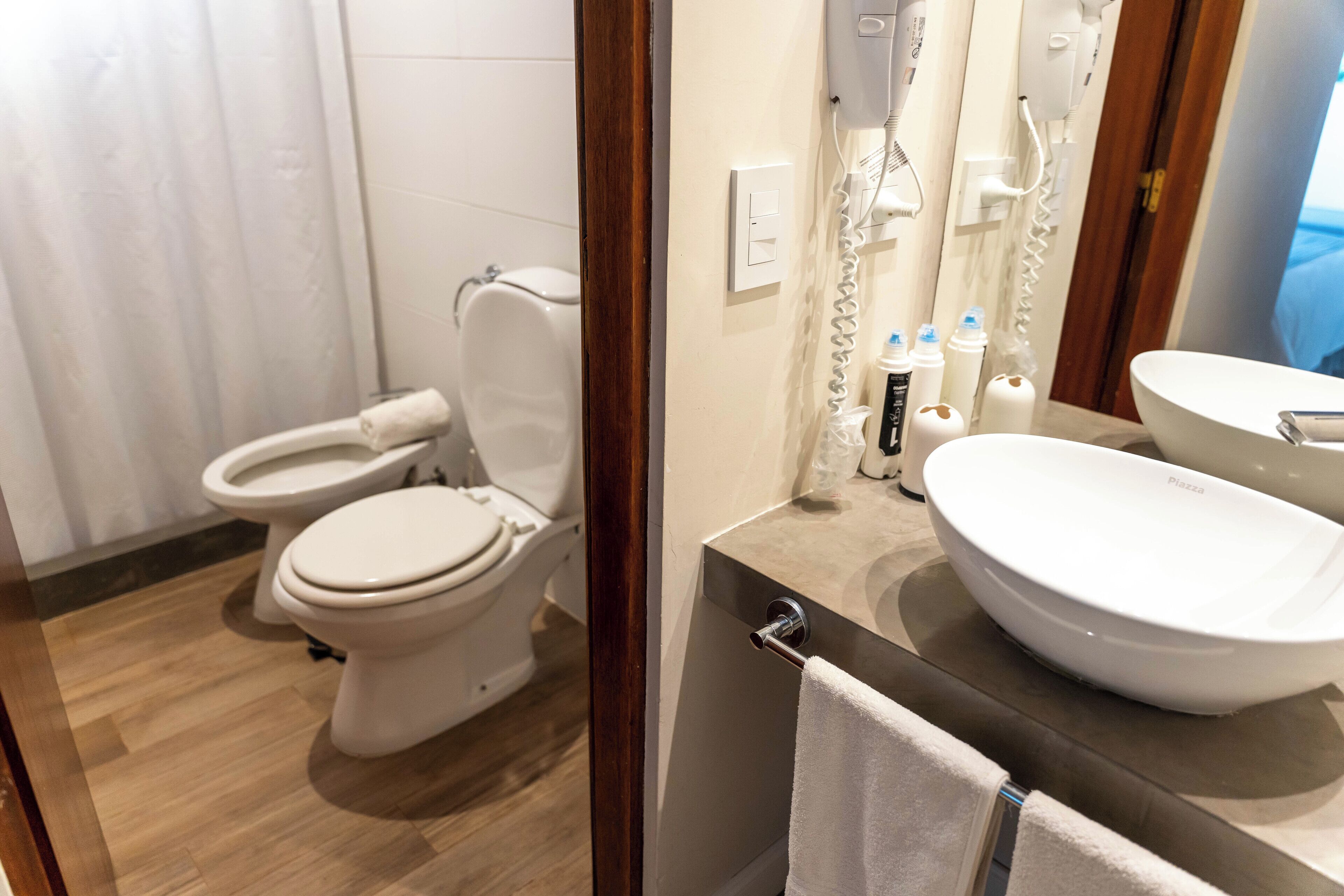 Un baño con dos inodoros, un lavamanos y un espejo.