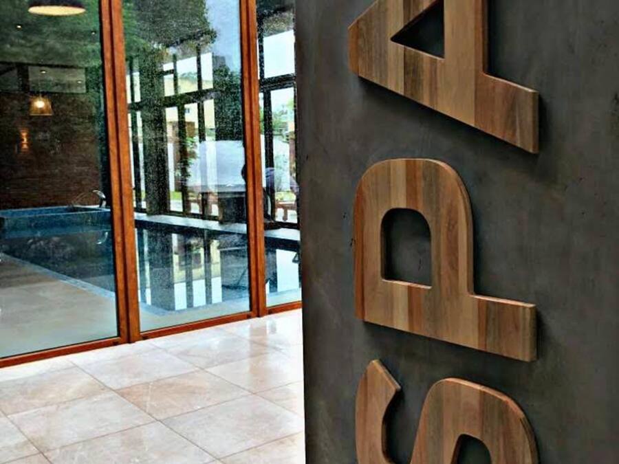 A modern interior with large glass windows, a wooden sign with letters, and a tiled floor.