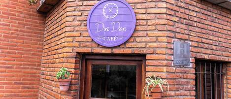 A brick building with a wooden door and a purple sign that reads "Din Don Café".