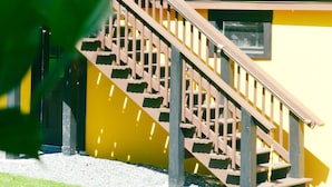 A two-story building with a yellow exterior, a wooden staircase, and a balcony. - Willow Pond Motel (Catskill)