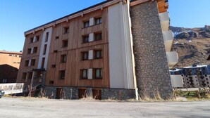 Edifício de vários andares com fachada de madeira e detalhes em pedra, apresentando varandas e amplas janelas.