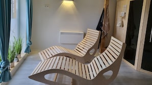 Ein Zimmer mit zwei Holz-Loungesesseln, einem Wandheizkörper und einem fensterbepflanzten Fenster mit Vorhängen.