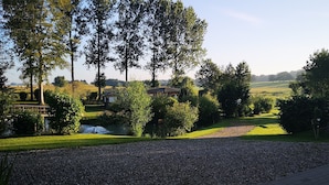 Ein Schotterweg führt zu einem Haus mit Blick auf ein Wiesenfeld und Bäume.
