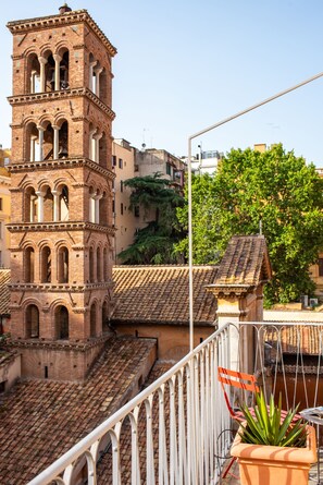 A terracotta-roofed building with a bell tower, a potted plant, and a white metal railing. - Sentho Roma (Rome)