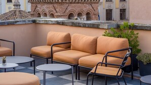 A rooftop terrace with a brick tower, outdoor seating, and a potted plant. - Sentho Roma (Rome)