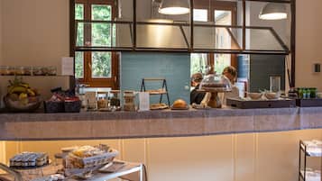A breakfast buffet area with various food items and a person preparing food.