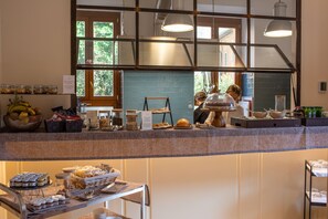 A breakfast buffet area with various food items and a person preparing food.