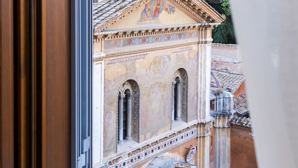 A view from a window of a building with classical architecture, including arched windows and decorative moldings. - Sentho Roma (Rome)