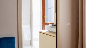 Une chambre d’hôtel avec une porte donnant sur une salle de bain et une petite kitchenette.