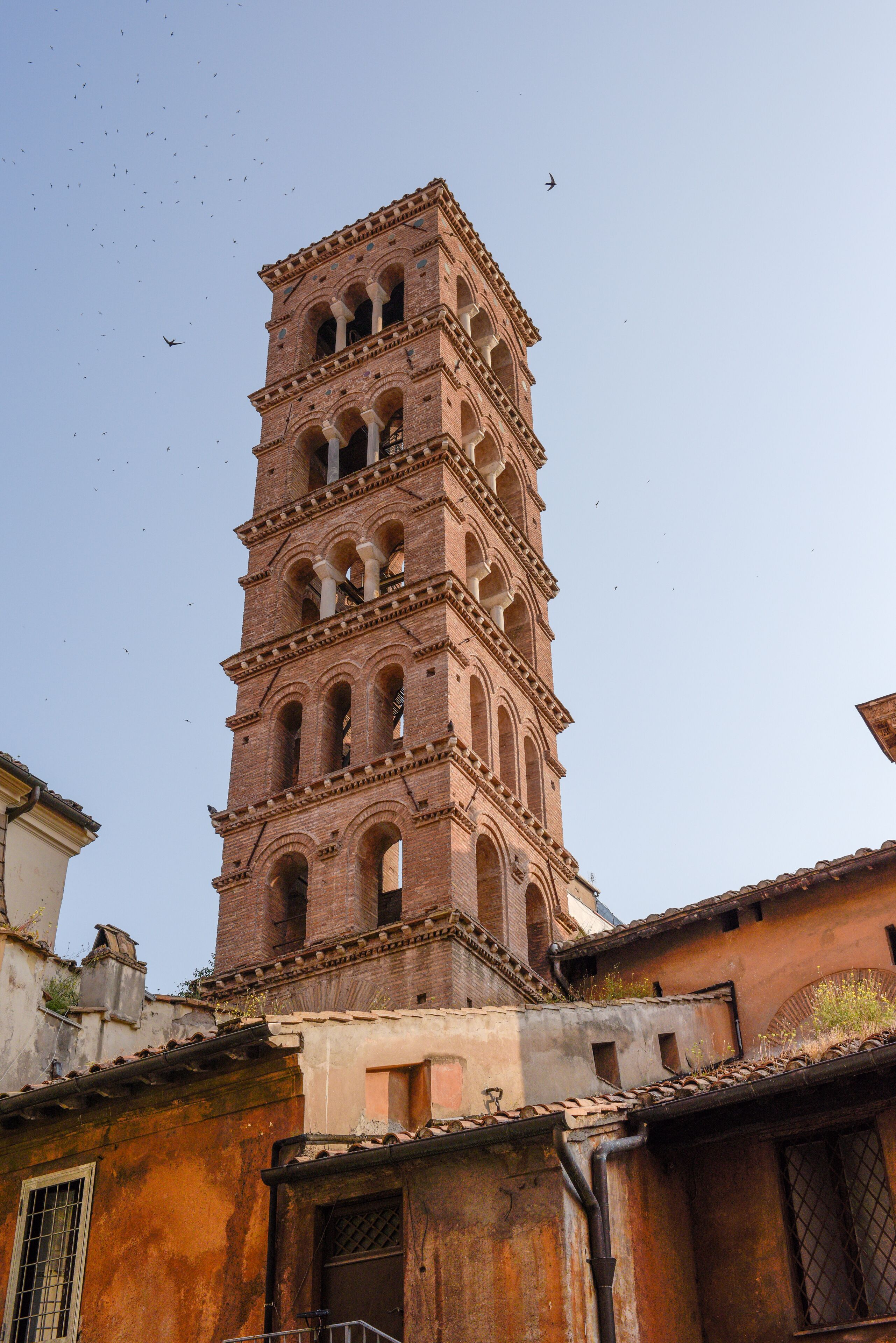 Uma torre alta, com vários níveis, janelas em arco e fachada de tijolos.