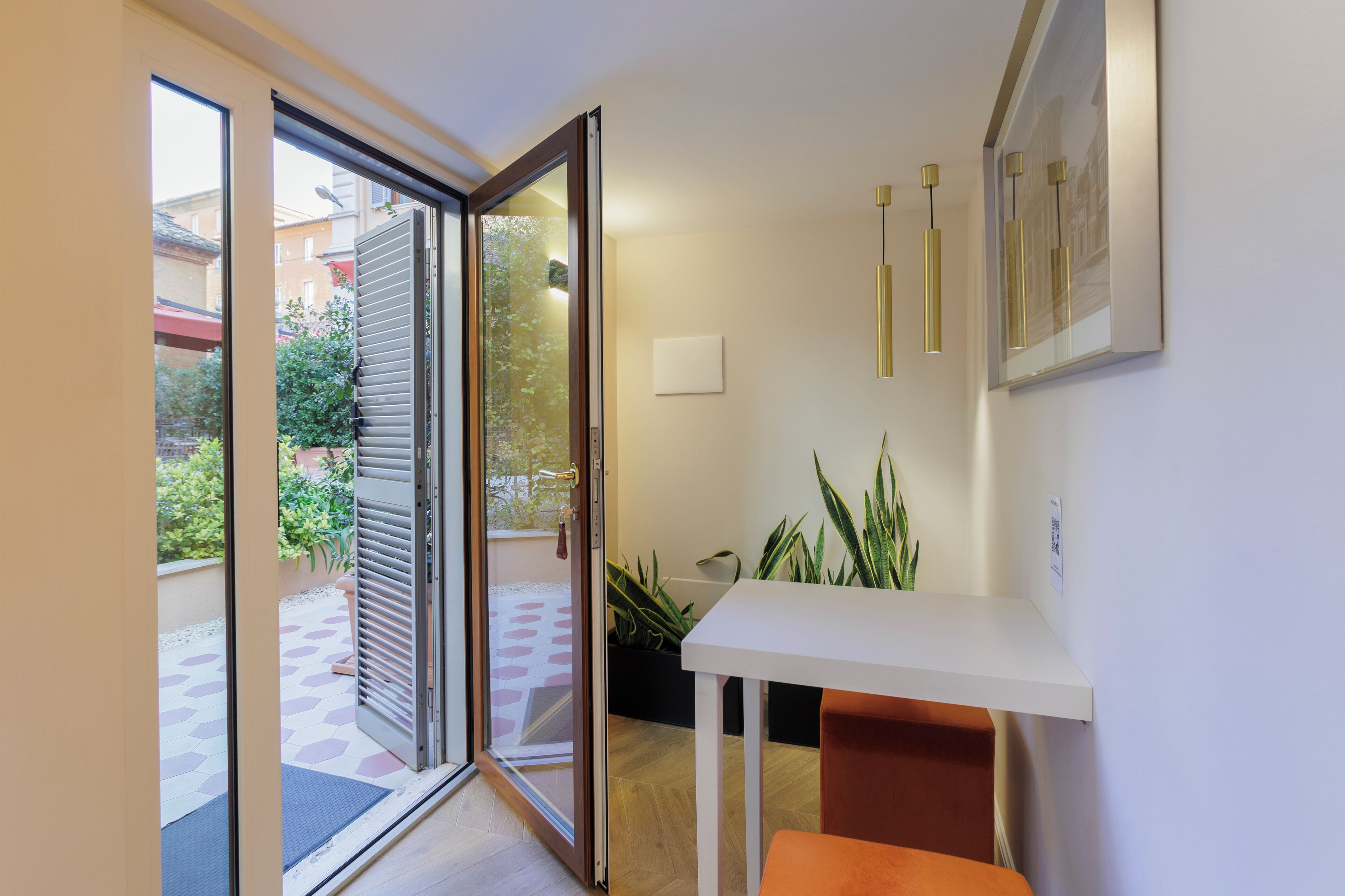A modern interior with a sliding glass door leading to an outdoor area, a white table with a plant, and a framed picture on the wall.