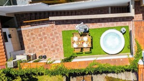 A rooftop patio with a hot tub, a dining table set, and a brick wall. - Spacious Duplex | Jacuzzi & Terrace by HostWise (Porto)
