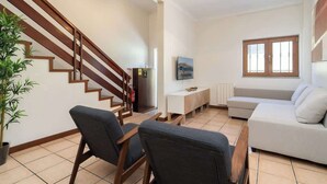 A living room with a staircase, a sofa, a TV, and a plant. - Spacious Duplex | Jacuzzi & Terrace by HostWise (Porto)
