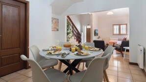 A dining area with a round table set for breakfast, including croissants, fruits, and juice. - Spacious Duplex | Jacuzzi & Terrace by HostWise (Porto)