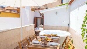 A patio with a wooden table set for breakfast, a white umbrella, and a small inflatable hot tub. - Spacious Duplex | Jacuzzi & Terrace by HostWise (Porto)