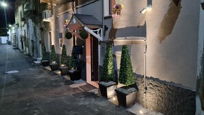 Un edificio con una entrada acogedora, árboles navideños en macetas y cestas de flores colgantes.