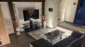Una sala de estar moderna con un televisor de pantalla plana, una mesa de centro de vidrio y un sofá oscuro.