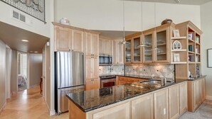 Una cocina amplia con armarios de madera, un refrigerador de acero inoxidable, un microondas y una encimera de granito.