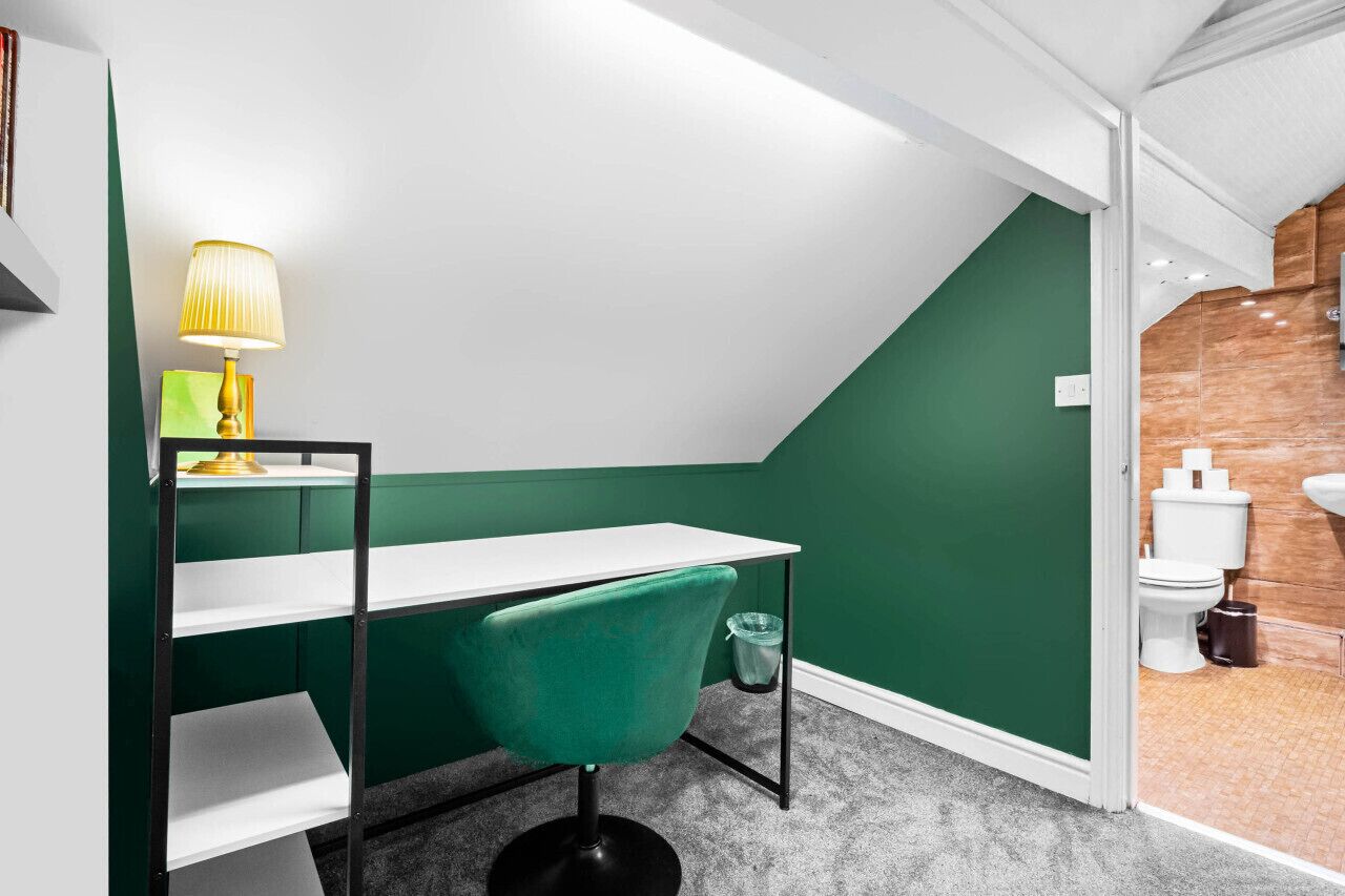 A modern bathroom with a green accent wall, a white sink, and a toilet.