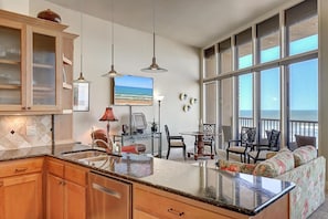 A kitchen with a large island, wooden cabinets, and a view of the ocean through large windows.