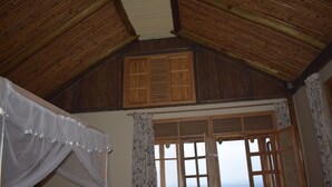 A room with a wooden ceiling, a large window with a view, and a bed with a canopy. - Rift Valley Game Lodge (Rubirizi)