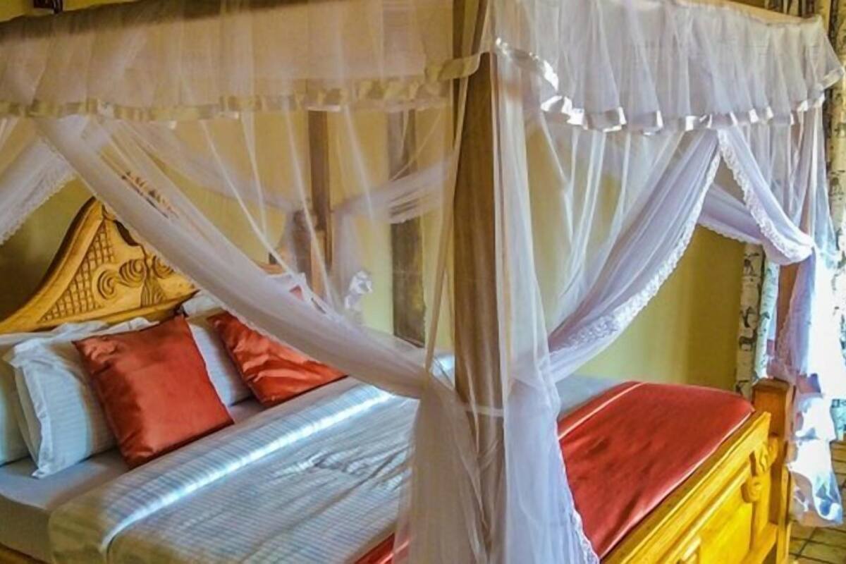 Una cama con dosel, almohadas y cabecera de madera.