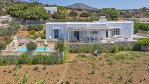Una villa moderna bianca con piscina, mobili da giardino e un giardino.