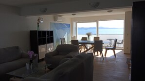 A living room with a sofa, a glass coffee table, a cabinet, and a dining area with chairs and a table.