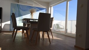 A dining area with a table, chairs, and a vase of dried flowers.