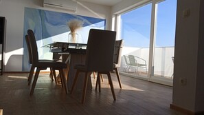 Un comedor con una mesa, sillas y un jarrón de flores secas.