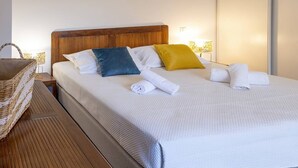 A neatly made bed with a wooden headboard, a bedside table with a woven basket, and a wall-mounted lamp. - Villa Renajolo. 6 pers, 3 min plage en voiture (STE LUCIE DE PORTO VECCHIO)