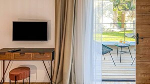 Een hotelkamer met een bed, een bureau, een televisie en uitzicht op het groen.