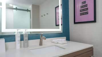 Un baño moderno con un espejo grande, un lavamanos y una cita inspiradora enmarcada en la pared.