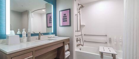 Un baño moderno con un espejo grande, dos lavamanos, una ducha con mampara de vidrio y una bañera con asiento para ducha.