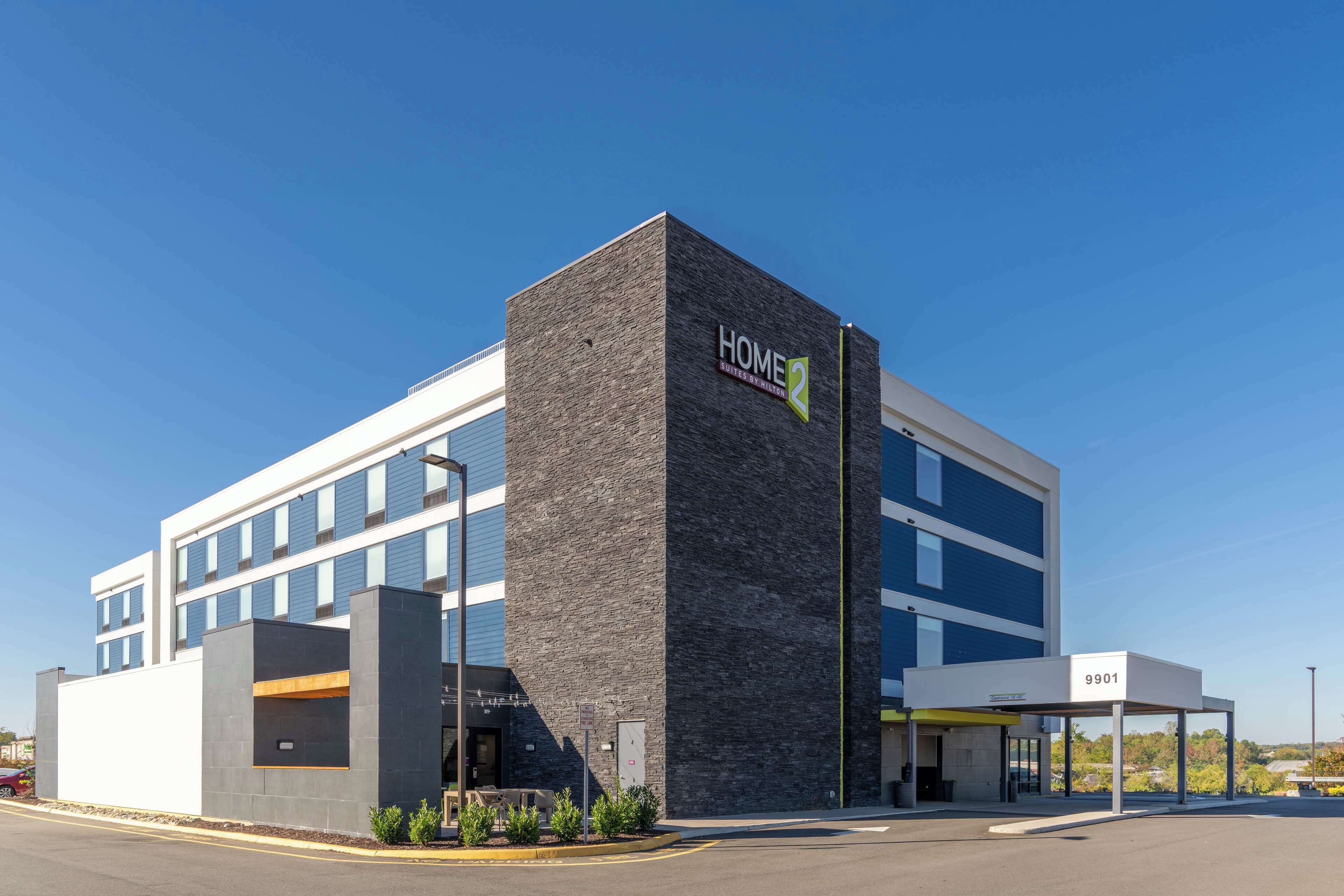 A modern building with a prominent "HOME 2" sign, large windows, and a covered entrance area.