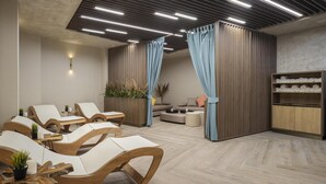 A spa room with wooden lounge chairs, a sofa, a wooden cabinet with towels, and a ceiling with linear lights. - Doubletree By Hilton Plovdiv Center (Plovdiv)