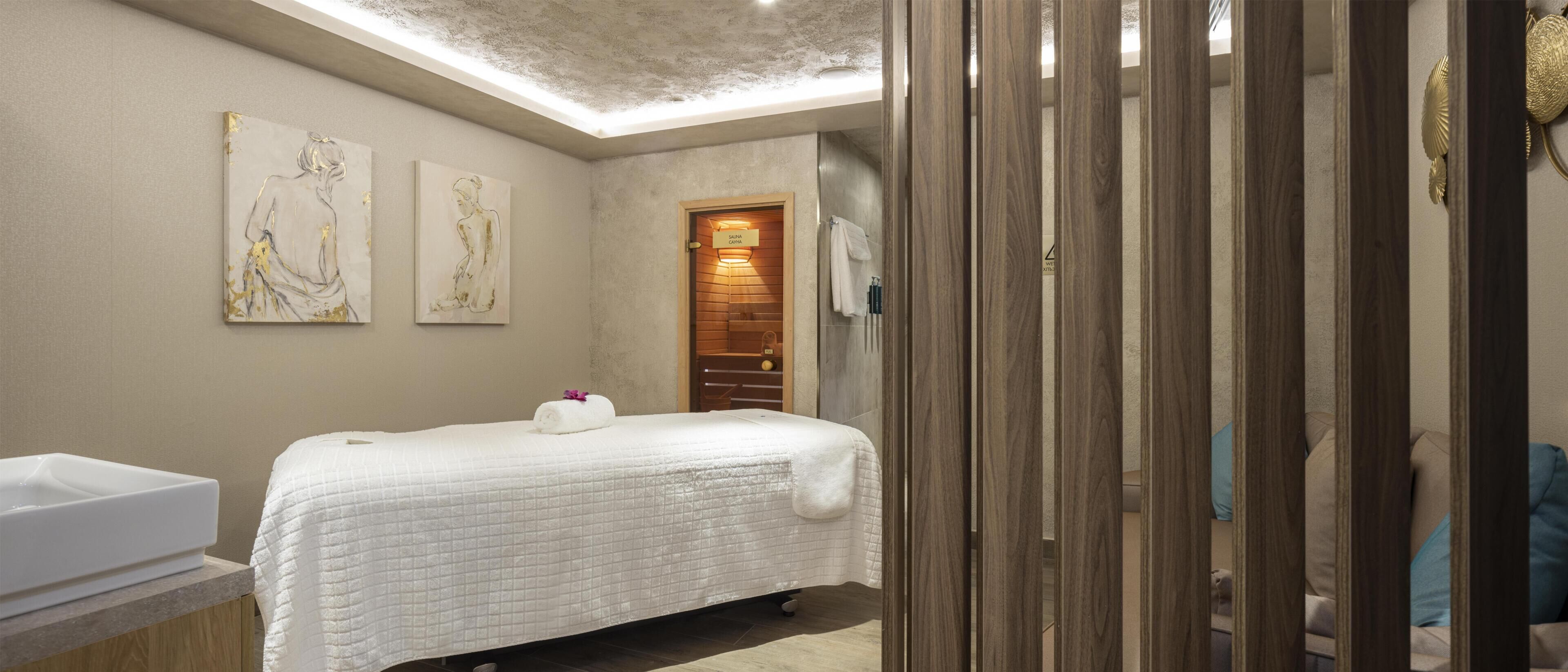 A bedroom with a bed, a wooden door, and a wall-mounted sink.