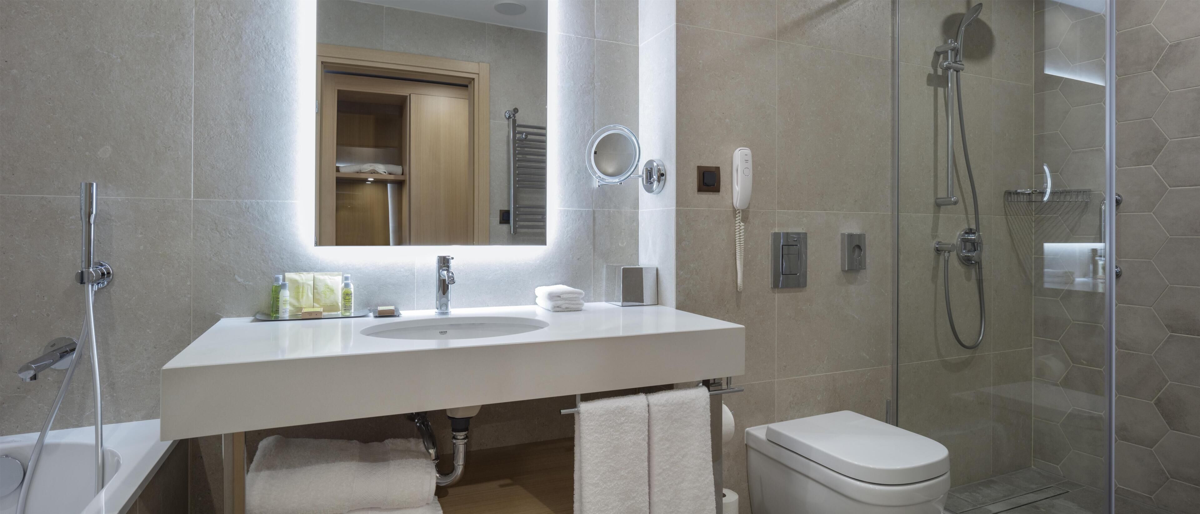A modern bathroom with a white sink, mirror, and shower.