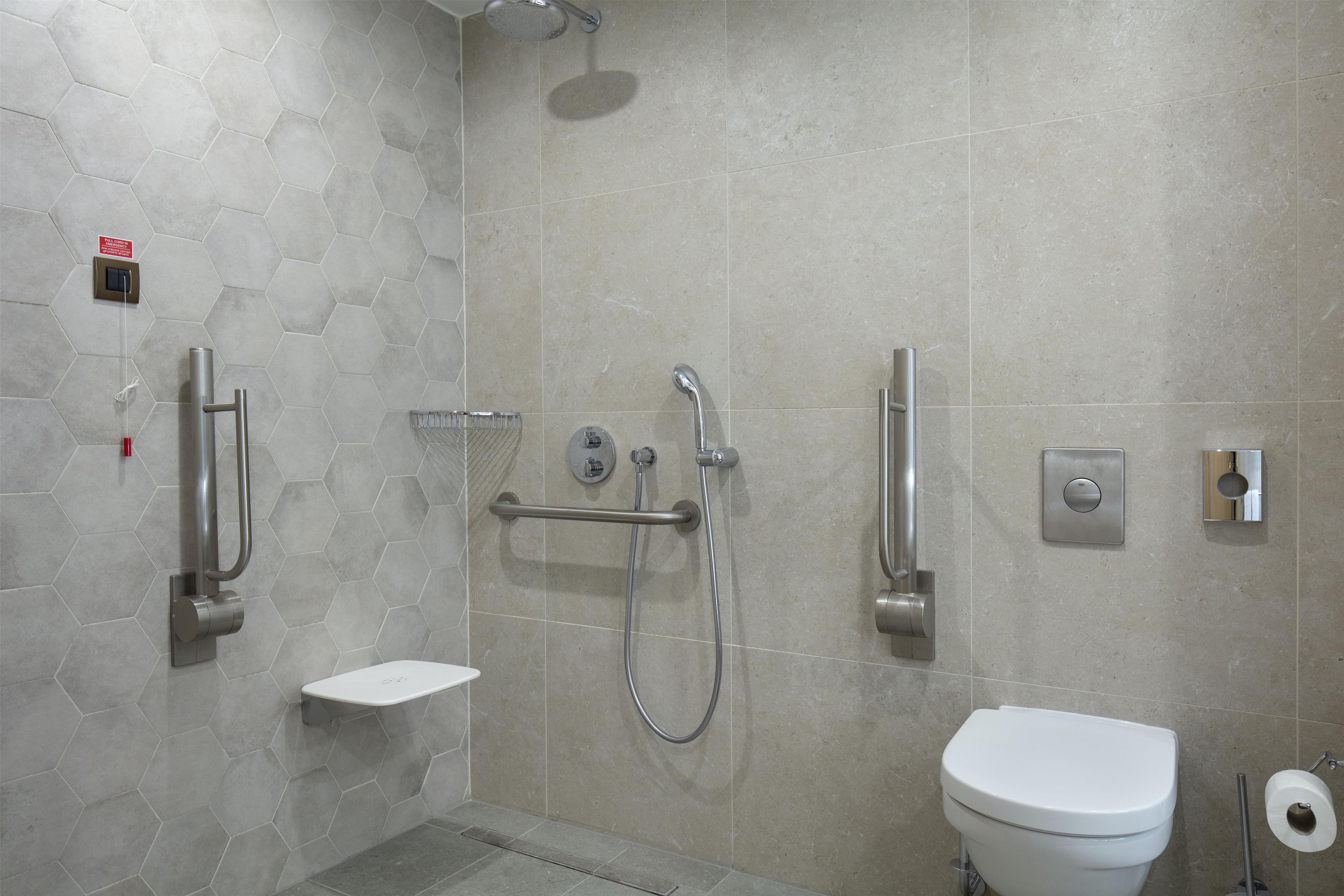 Un baño moderno con ducha, inodoro y un pequeño estante.